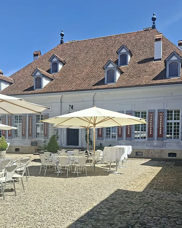 Innenhof von Schloss Thunstetten mit gedeckten Stehtischen und Sonnenschirmen für den Hochzeitsapéro.