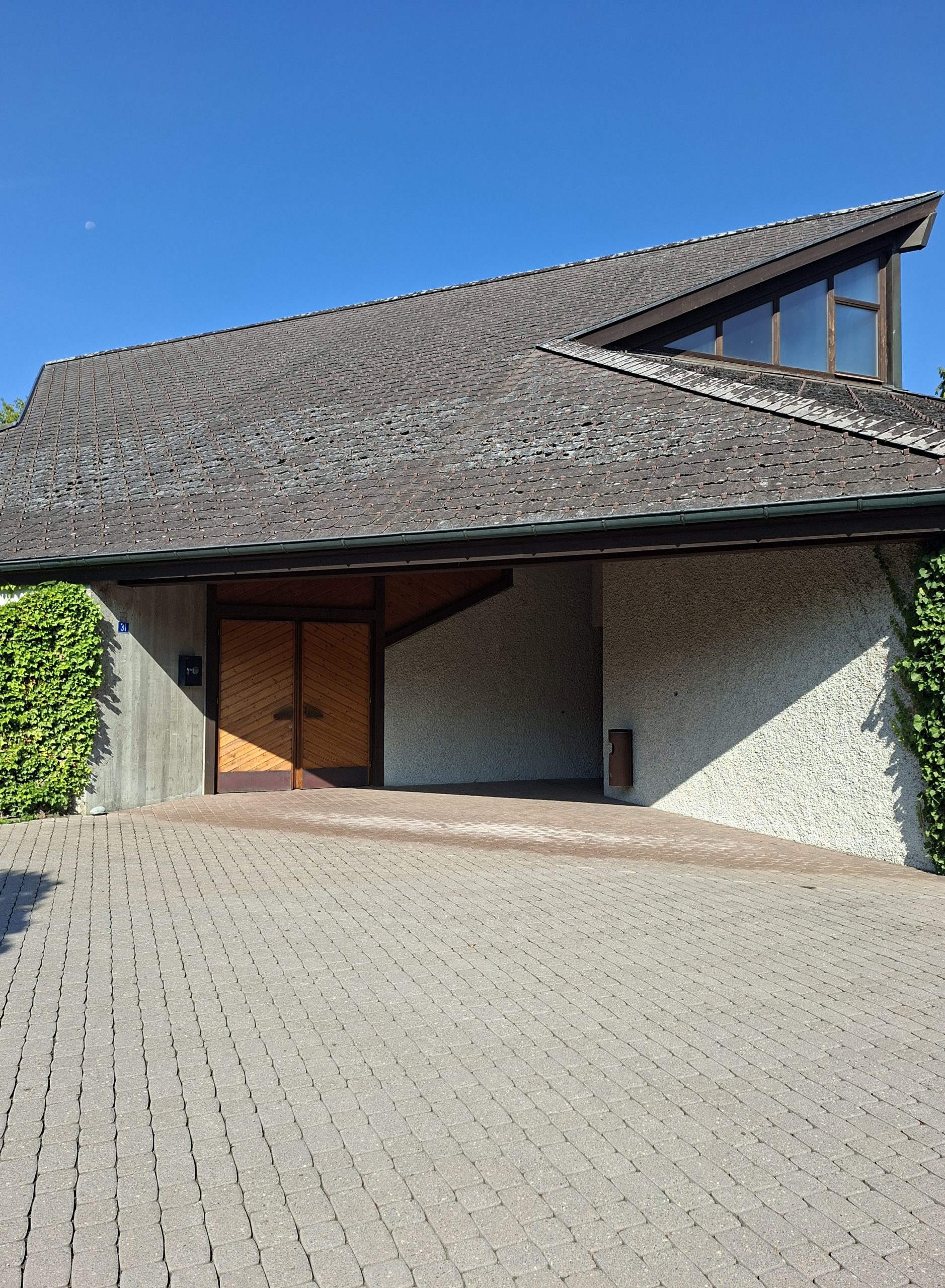 Aussenansicht der Friedhofskapelle Affoltern am Albis mit grossem Schrägdach und Holzeingang
