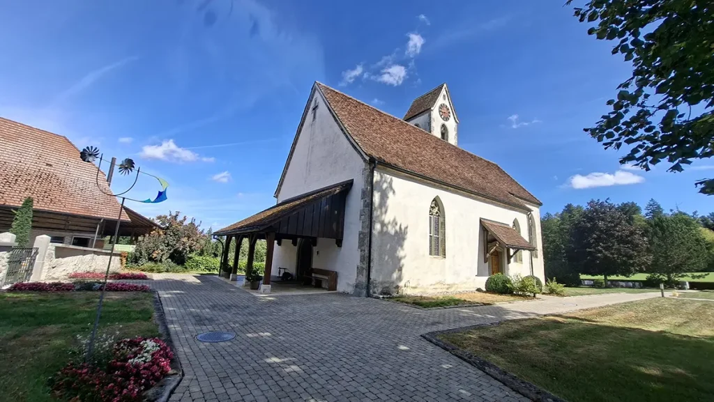 Kleine Kirche Seeberg mit weissem Mauerwerk und rotem Ziegeldach bei blauem Himmel